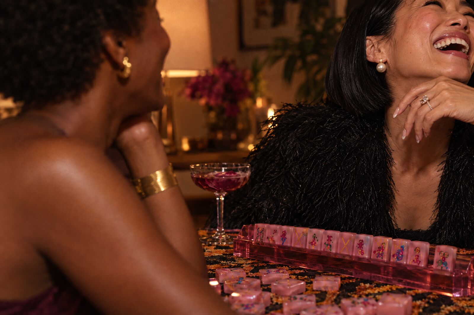 Two women laughing at an evening mahjong table